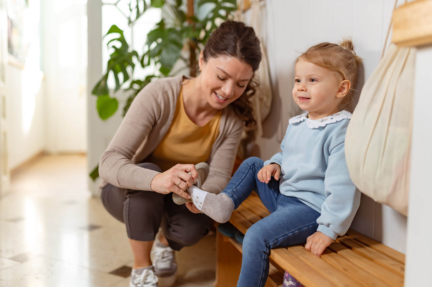 Mother helping her young daughter put on shoes, symbolising everyday parenting and child arrangements.