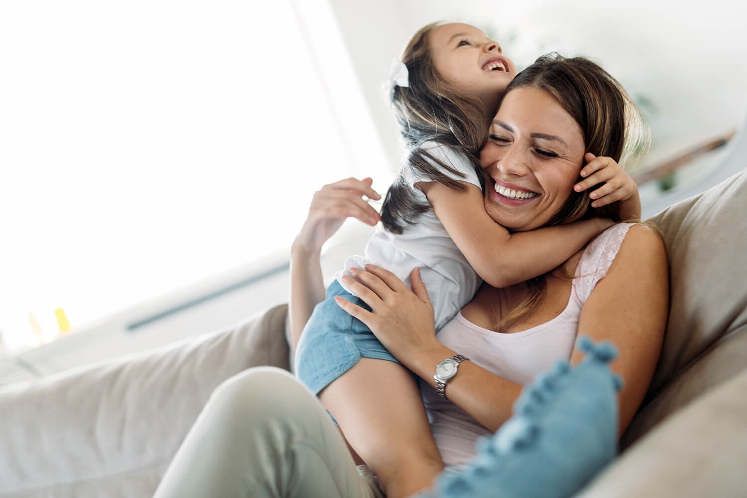Mother hugging daughter on sofa, representing emotional support and child custody arrangements in Cheshire.