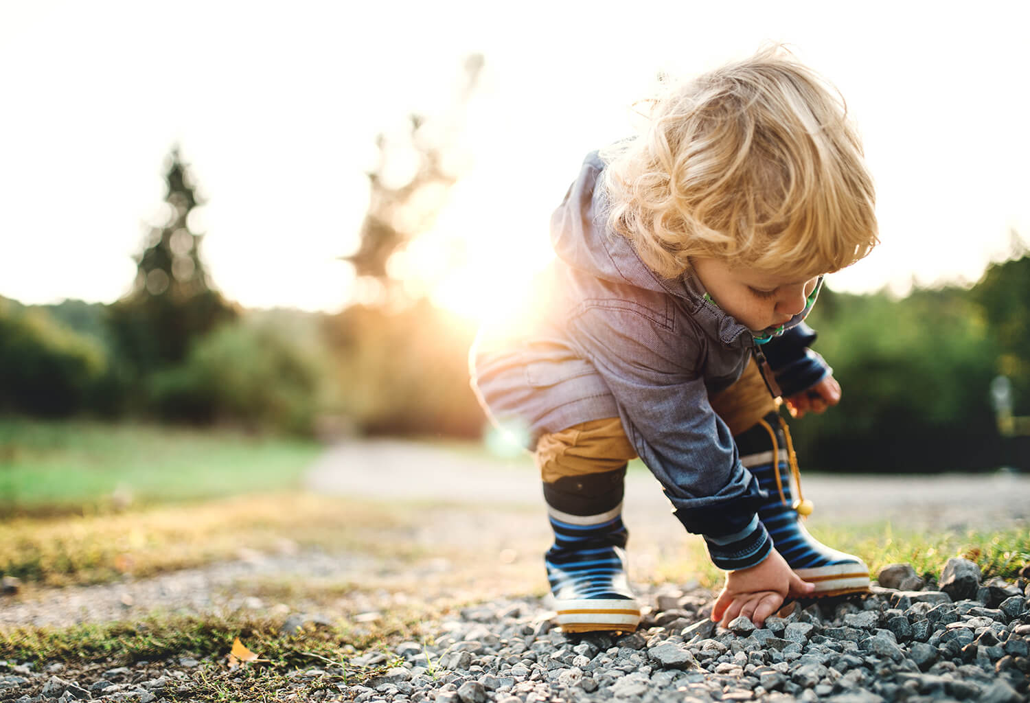 A young blonde child plays outside wearing a coat.
